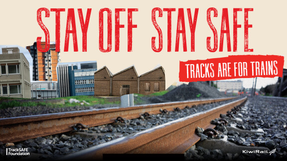 Campaign poster for Rail Safety week. Large bold tex tin red reads "Stay off, stay safe, tracks are for trains". The image shows a close up of train tracks with photoshopped buildings in the background. TrackSAFE Foundation logo in white on nottom left corner and KiwiRail logo in bottom right corner.